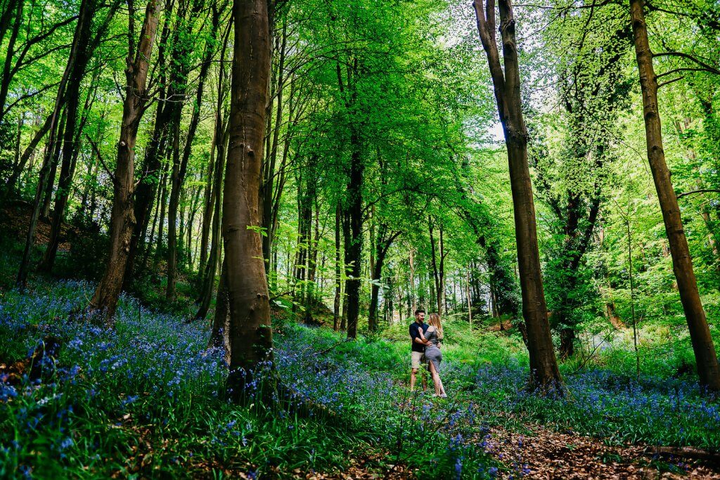 Soon to be bride and groom kissing under the trees amongst the bluebells of leigh woods in bristol