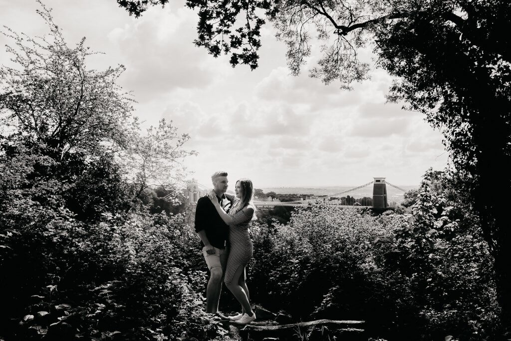 Engaged couple kissing with Bristol suspension bridge in the background